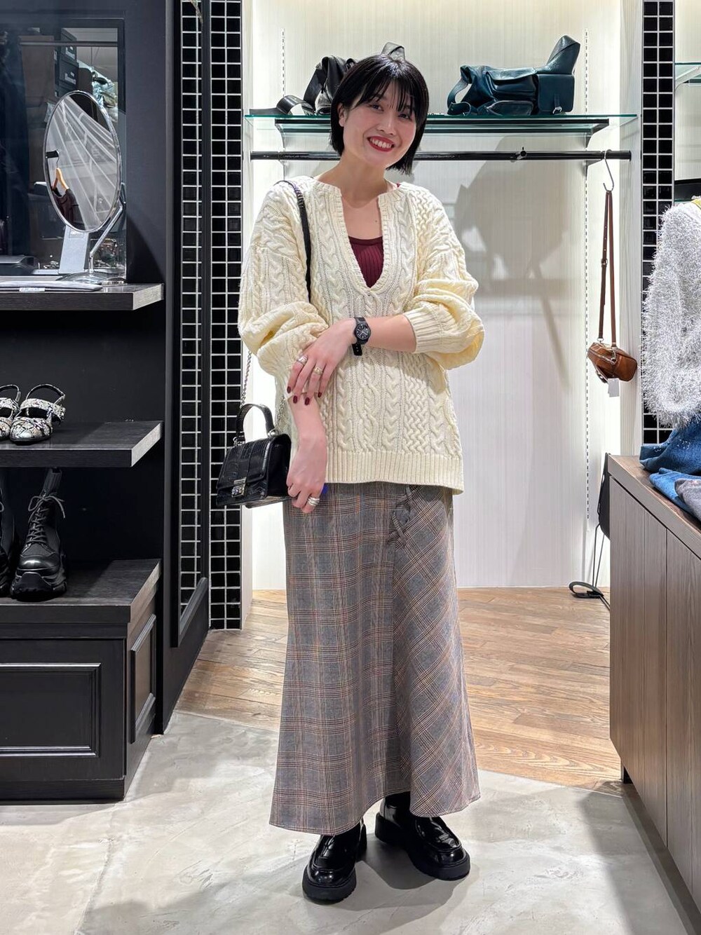 レッド系のタンクトップ、ブラック系のハンドバッグ、ホワイト系のニット/セーターを着用したレディースの秋コーディネートの1枚目の写真