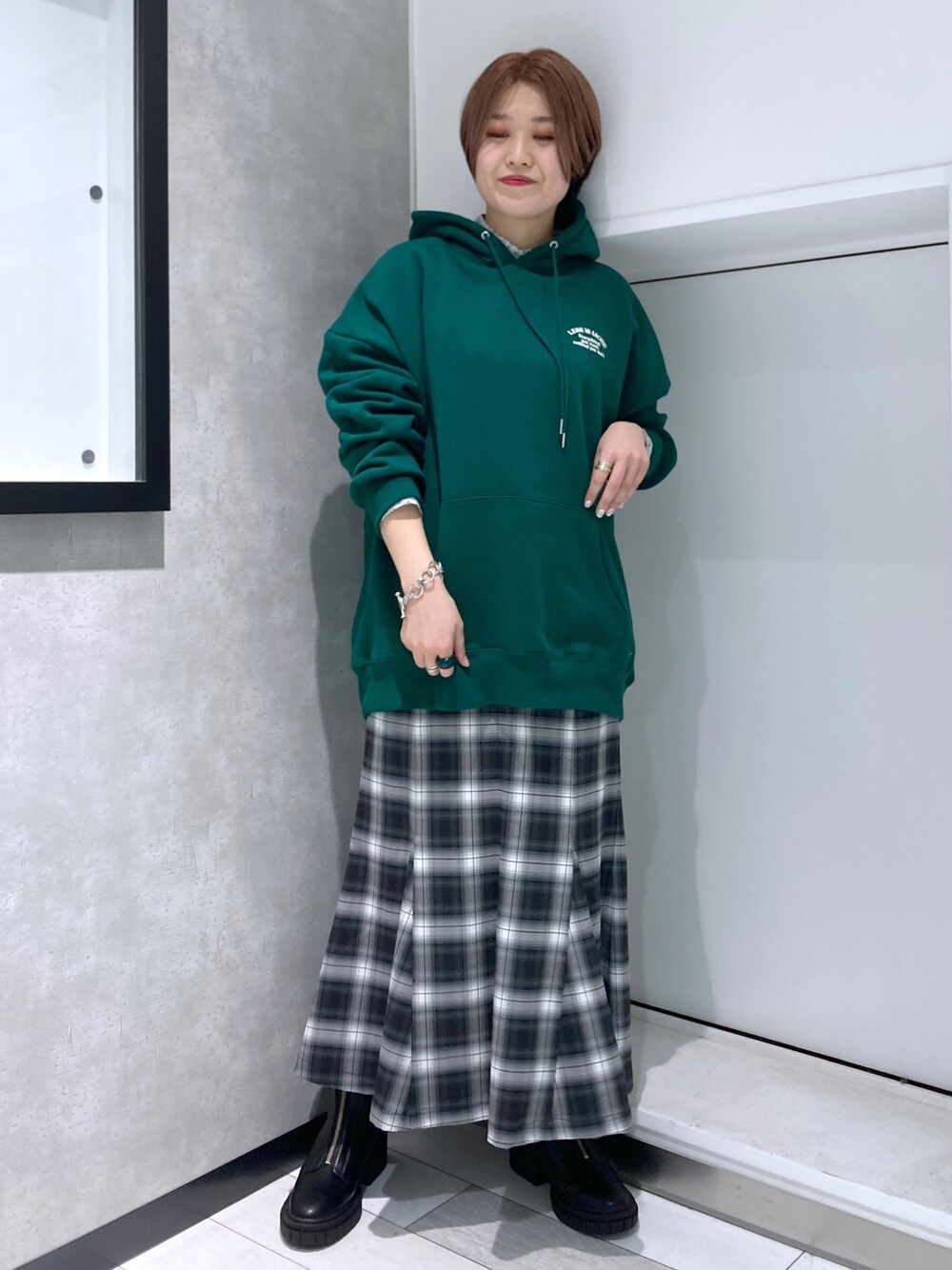 グリーン系のパーカー、ブラック系のスカート、ブラック系のブーツを着用したレディースの冬コーディネートの5枚目の写真