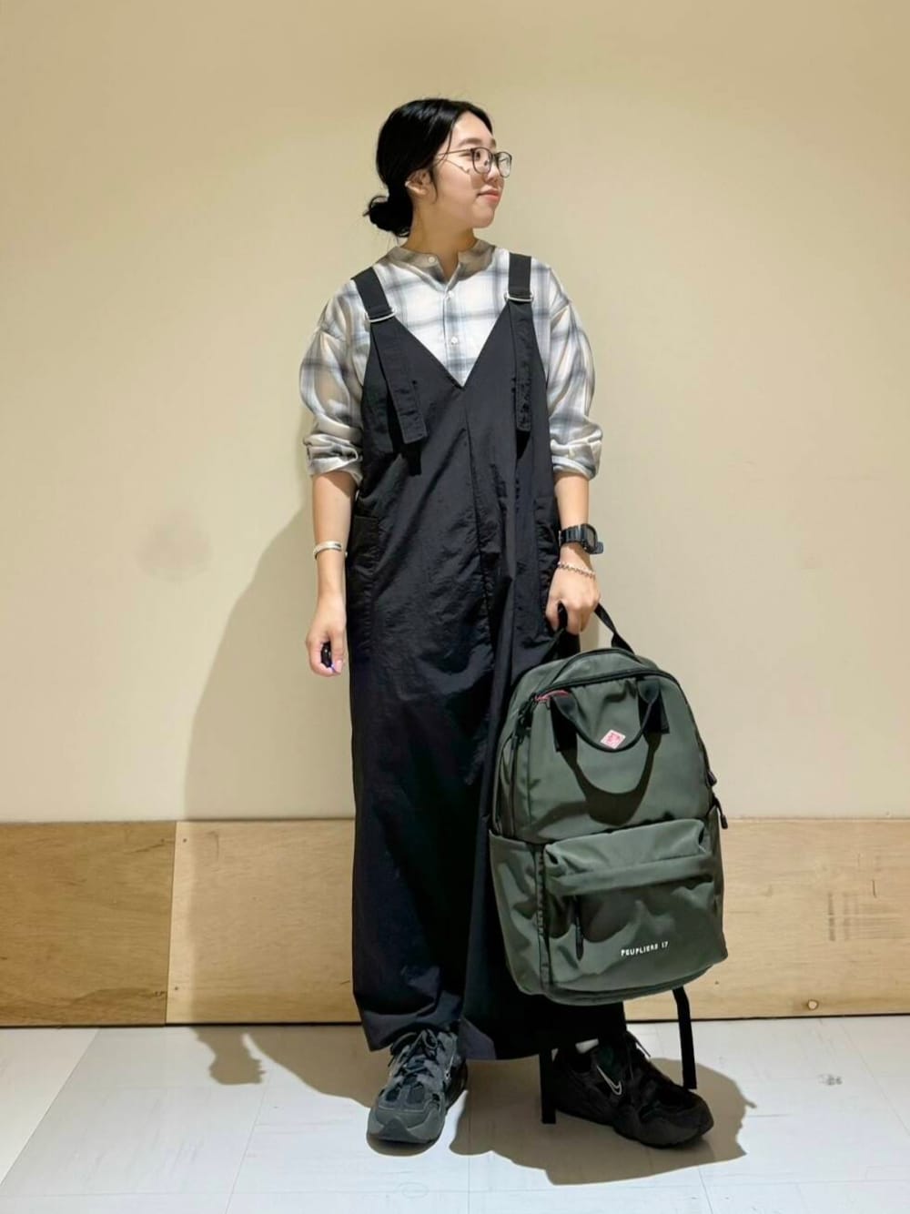 ブラック系のワンピース、グレー系のシャツ/ブラウス、グリーン系のバックパック/リュックを着用したレディースの秋コーディネートの1枚目の写真