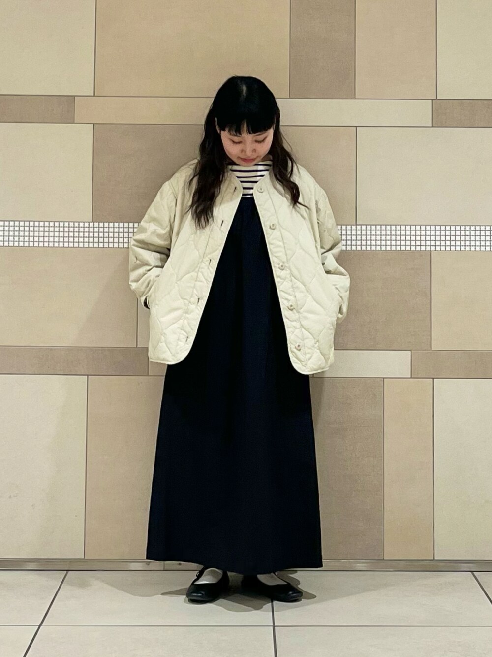 ベージュ系のダウンジャケット/コート、ブラック系のワンピース、ホワイト系のTシャツ/カットソーを着用したレディースの冬コーディネートの1枚目の写真