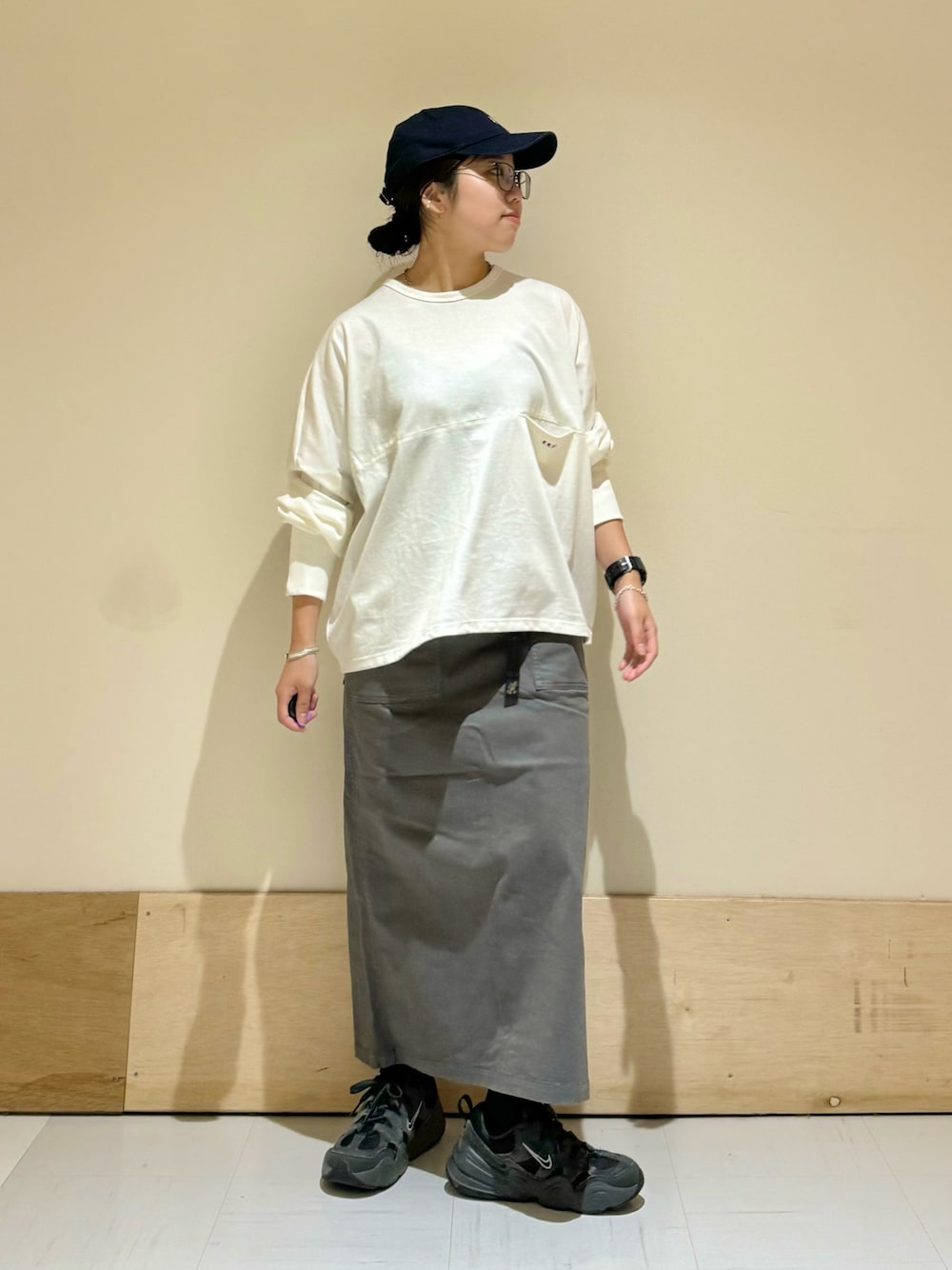グレー系のスカート、ホワイト系のTシャツ/カットソーを着用したレディースの秋コーディネートの1枚目の写真