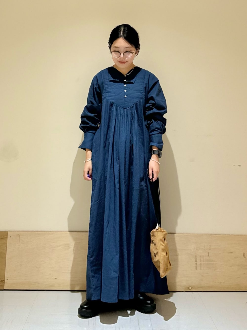 ブラック系のブーツ、ブラウン系のショルダーバッグ、ブルー系のワンピースを着用したレディースの秋コーディネートの1枚目の写真