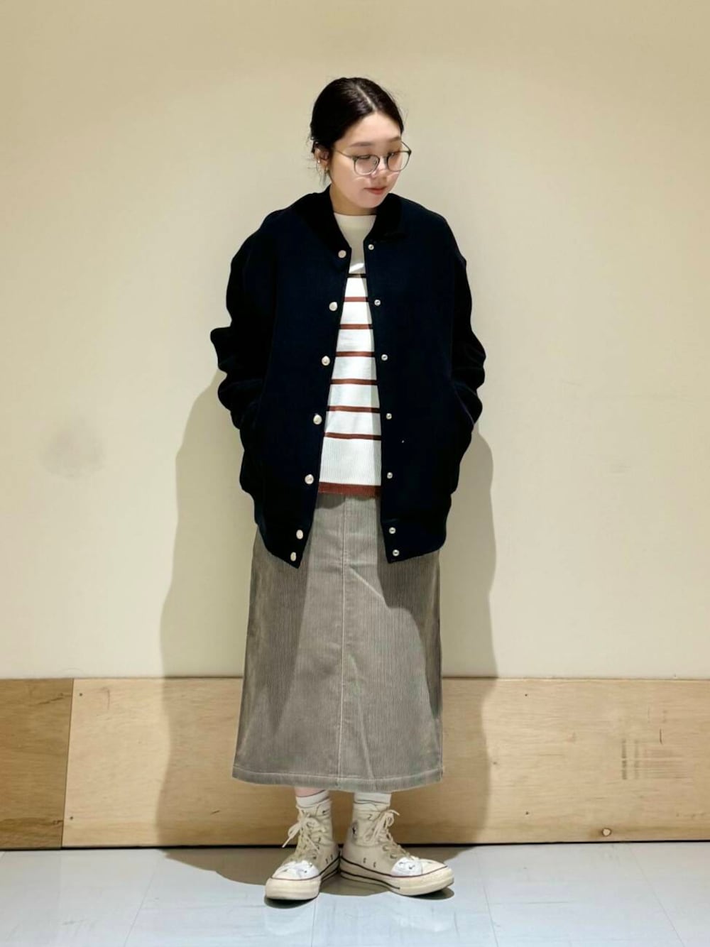 オレンジ系のニット/セーター、ブルー系のスタジャン、ブラウン系のスカートを着用したレディースの冬コーディネートの1枚目の写真