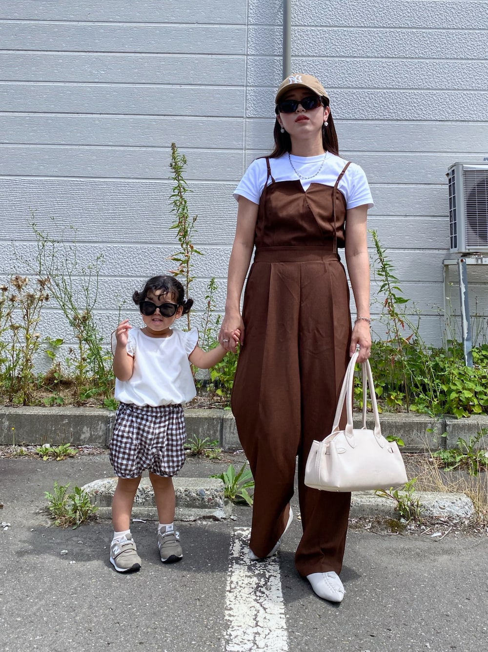 ブラック系のボストンバッグ、ベージュ系のキャップを着用したレディースの夏コーディネートの1枚目の写真