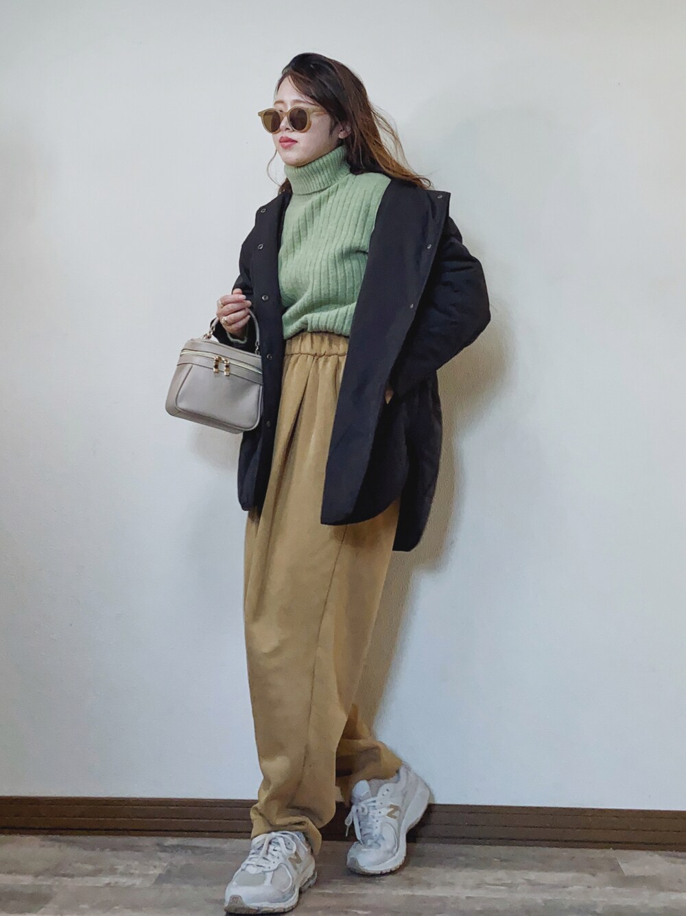 グリーン系のニット/セーター、ベージュ系のスウェットパンツ、グレー系のスニーカーを着用したレディースの冬コーディネートの1枚目の写真