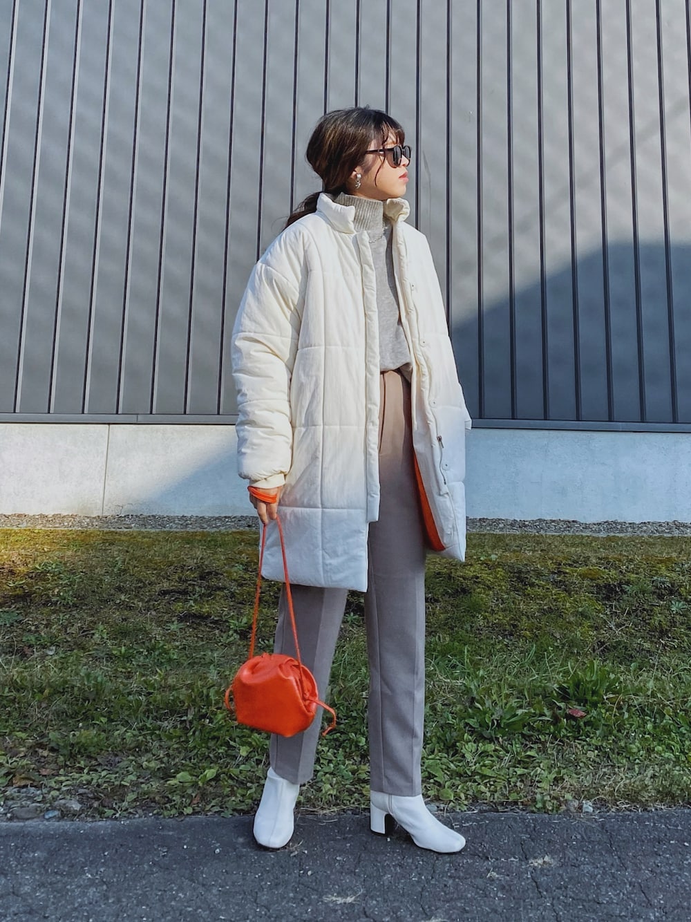 ホワイト系のダウンジャケット/コート、オレンジ系のショルダーバッグ、グレー系のニット/セーターを着用したレディースの秋コーディネートの1枚目の写真