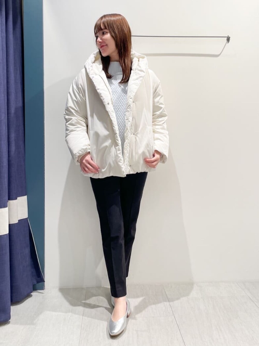 ホワイト系のダウンジャケット/コート、ブルー系のニット/セーター、ブラック系のその他パンツを着用したレディースの冬コーディネートの1枚目の写真