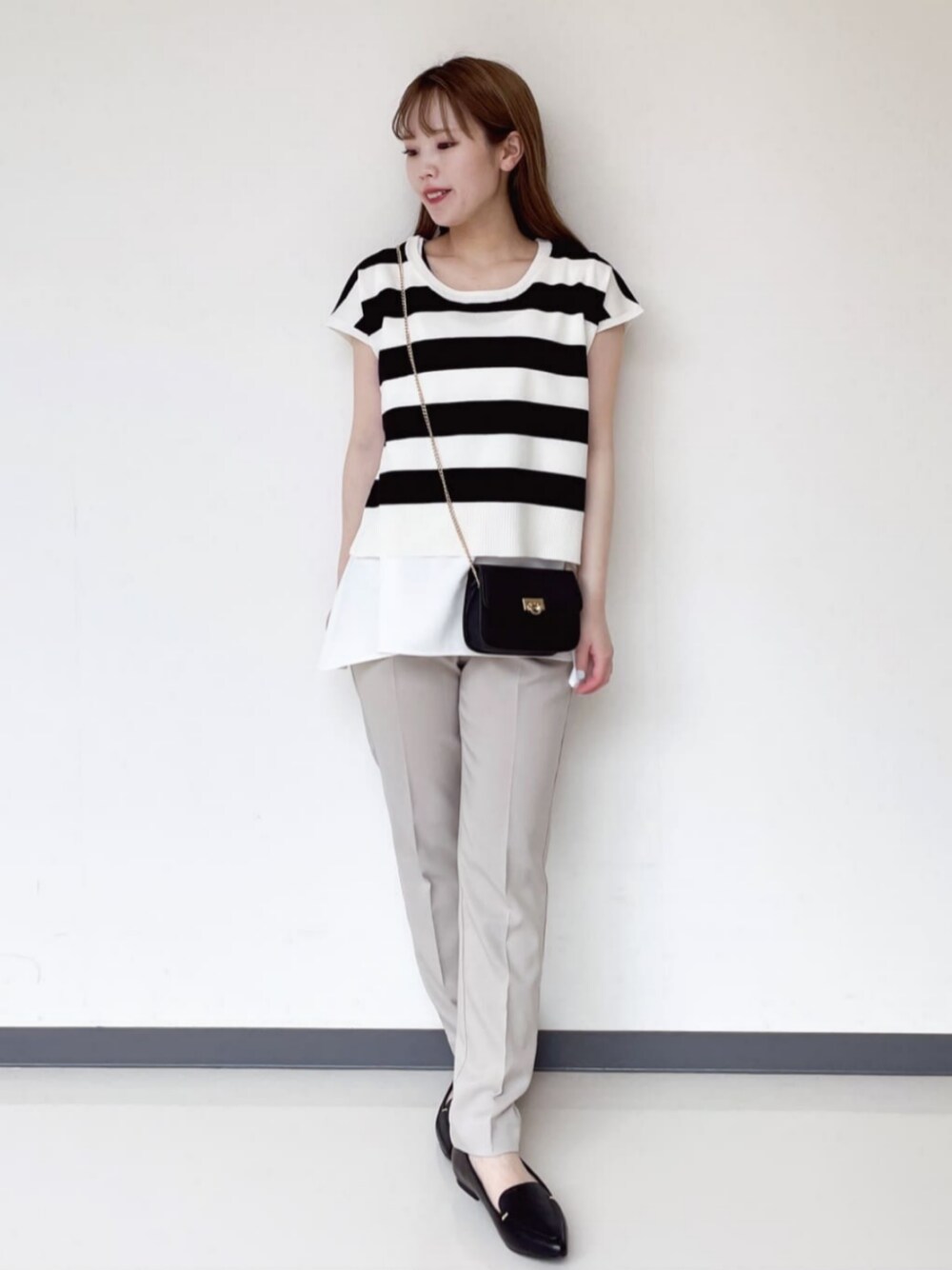 ブラック系のショルダーバッグ、ホワイト系のその他トップス、ベージュ系のその他パンツを着用したレディースの夏コーディネートの1枚目の写真