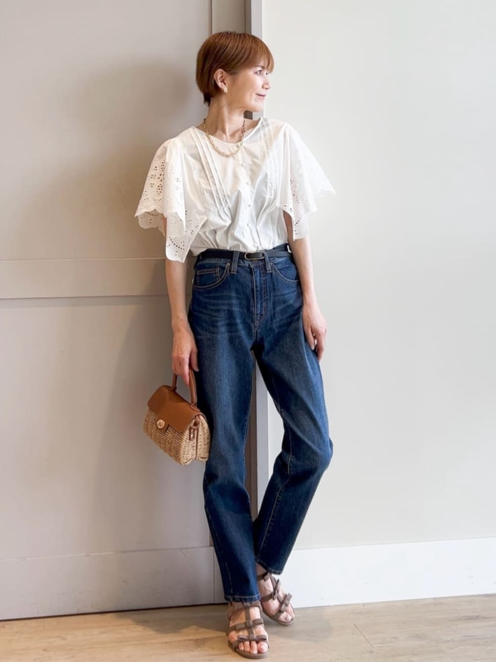 ブルー系のデニムパンツ、イエロー系のショルダーバッグ、ベージュ系のサンダルを着用したレディースの夏コーディネートの1枚目の写真