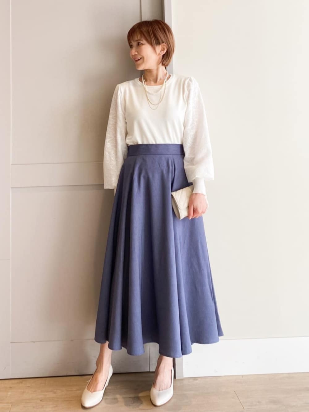 ホワイト系のパンプス、ホワイト系のショルダーバッグ、ブルー系のスカートを着用したレディースの冬コーディネートの1枚目の写真