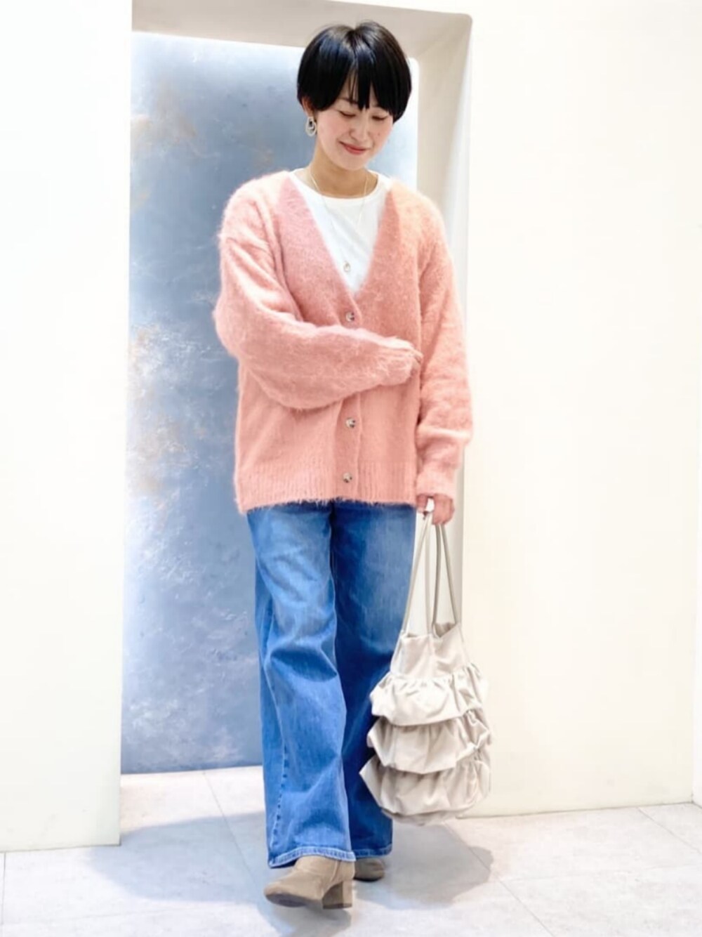ブルー系のデニムパンツ、ホワイト系のTシャツ/カットソー、グレー系のブーツを着用したレディースの秋コーディネートの1枚目の写真