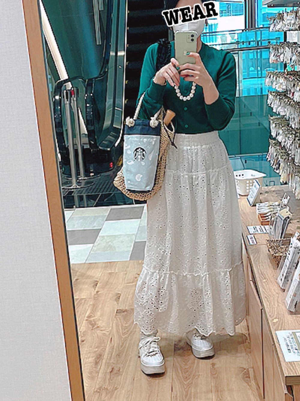 ホワイト系のスカート、グリーン系のカーディガン/ボレロ、ベージュ系のバッグを着用したレディースの夏コーディネートの1枚目の写真