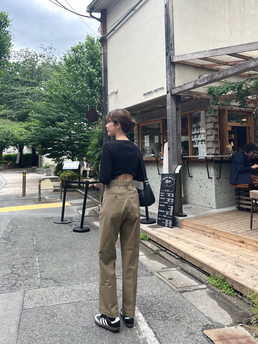 ブラック系のTシャツ/カットソー、ベージュ系のチノパンツ、ブラック系のスニーカーを着用したレディースの春コーディネートの1枚目の写真