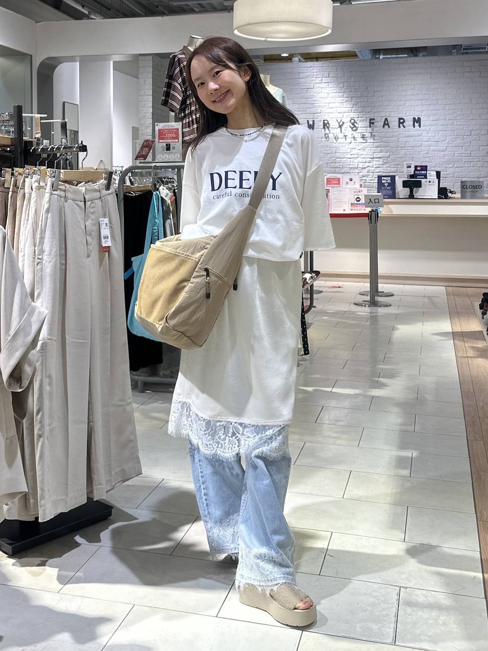 ベージュ系のショルダーバッグ、ホワイト系のTシャツ/カットソー、ブルー系のデニムパンツを着用したレディースの夏コーディネートの1枚目の写真