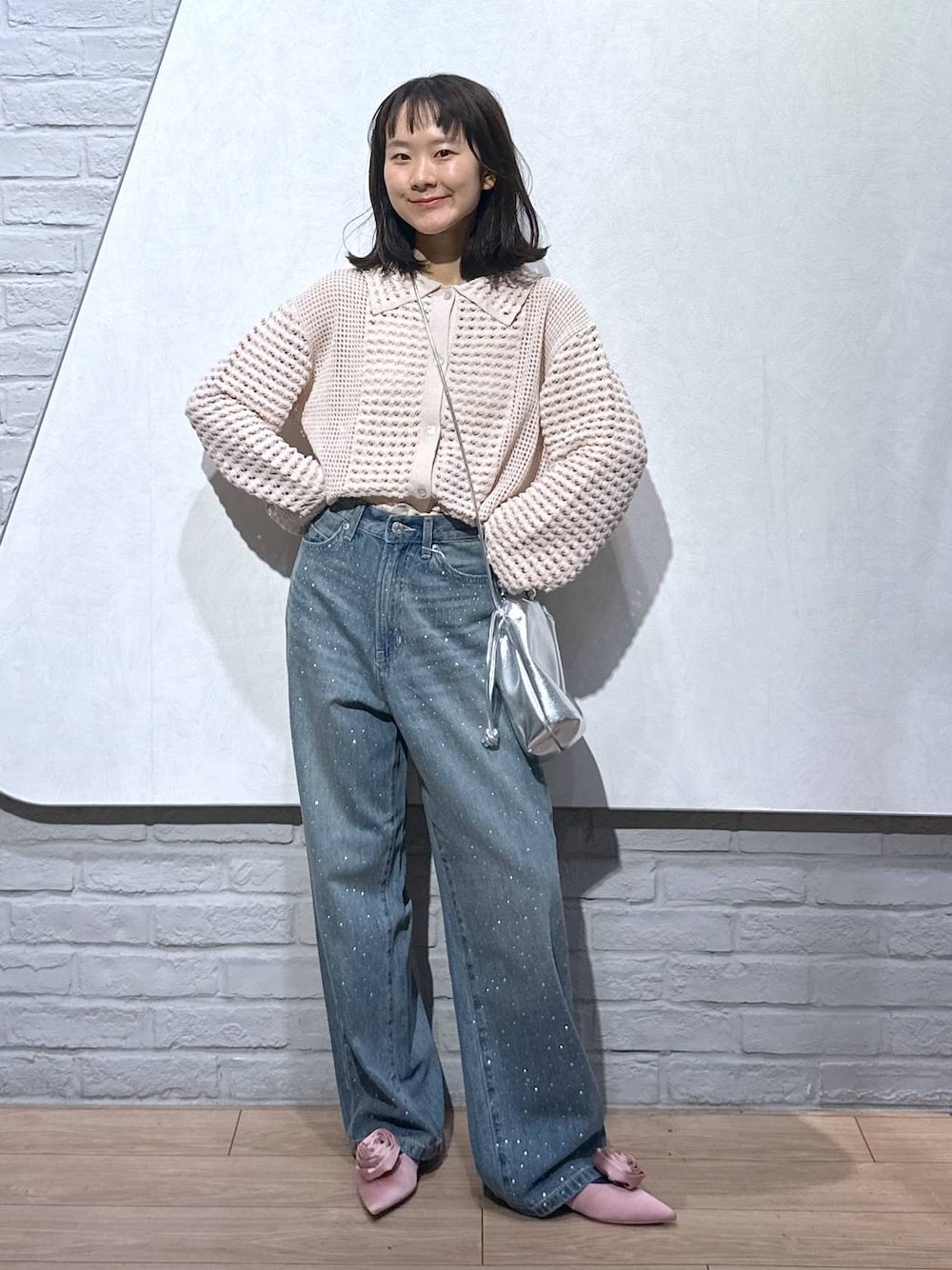 ピンク系のパンプス、シルバー系のショルダーバッグ、ブルー系のデニムパンツを着用したレディースの秋コーディネートの1枚目の写真