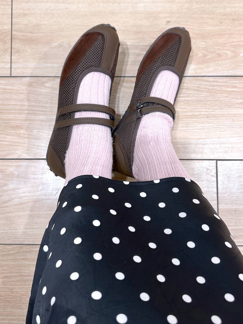 ブラック系のスカート、ブラウン系のスニーカーを着用したレディースの春コーディネートの1枚目の写真