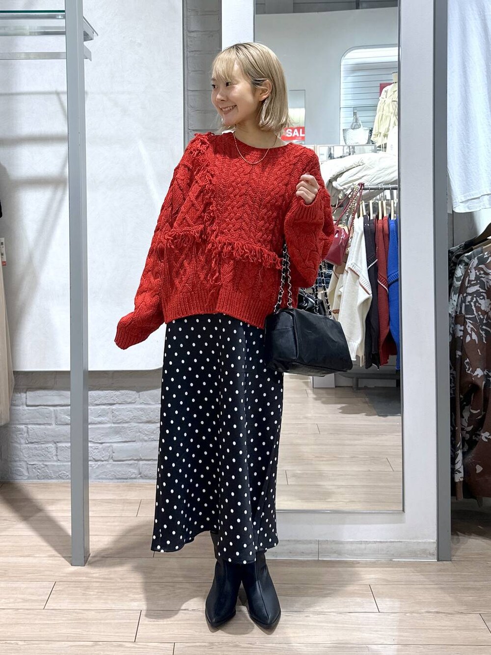 ブラック系のスカート、レッド系のポロシャツ、ブラック系のブーツを着用したレディースの冬コーディネートの1枚目の写真