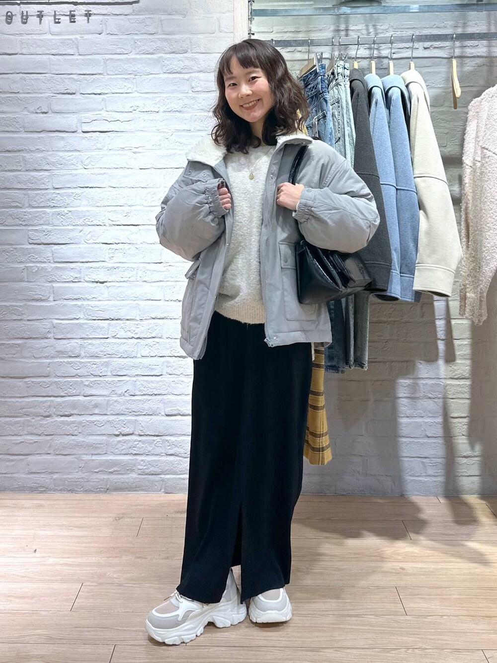 ブラック系のスカート、グリーン系のブルゾン、ベージュ系のスニーカーを着用したレディースの冬コーディネートの1枚目の写真