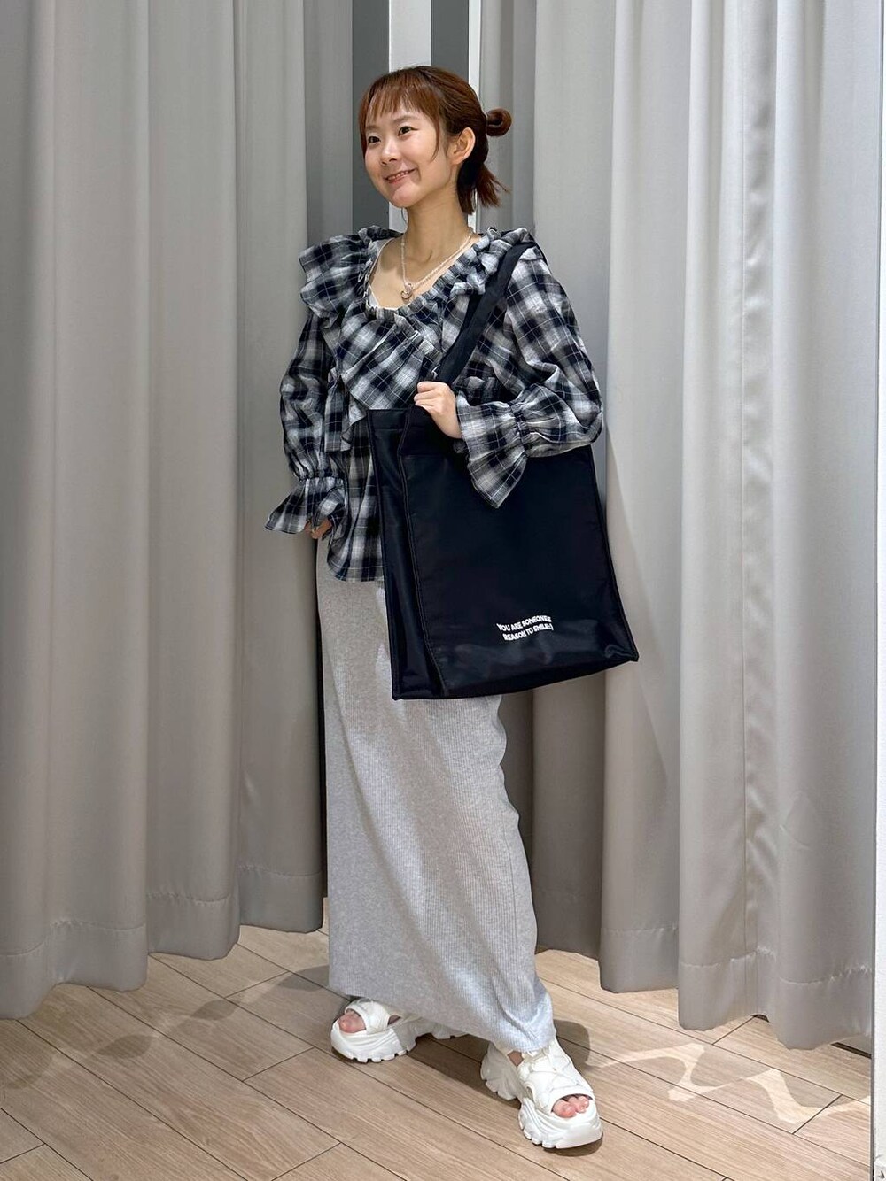 グレー系のスカート、ホワイト系のサンダル、ブラック系のトートバッグを着用したレディースの夏コーディネートの1枚目の写真