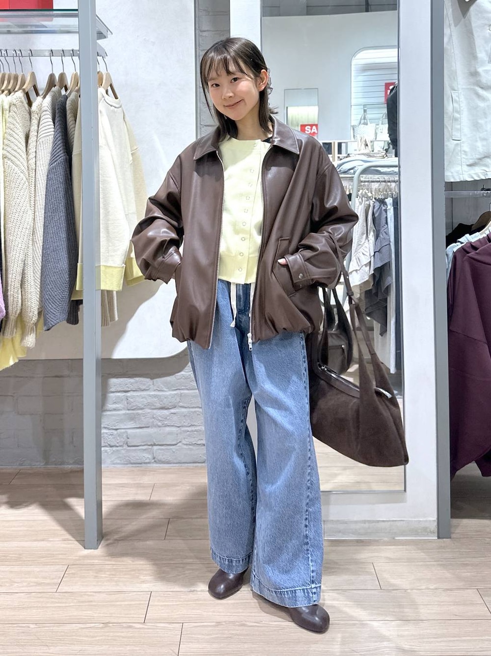 ブルー系のデニムパンツ、ブラウン系のブルゾン、ブラウン系のサンダルを着用したレディースの春コーディネートの1枚目の写真