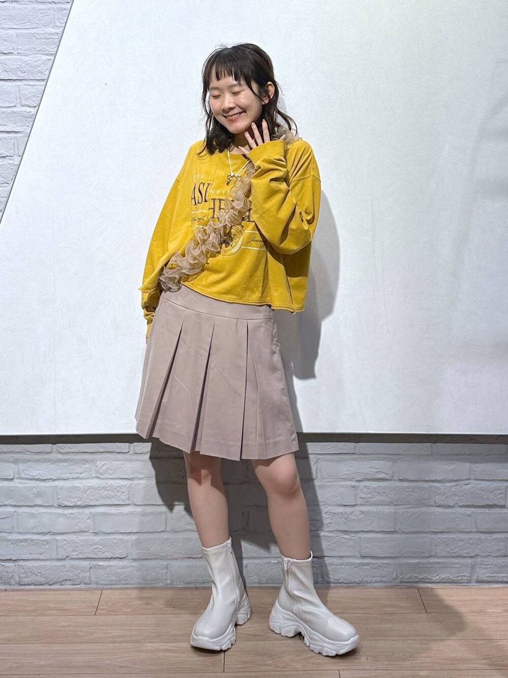 ホワイト系のブーツ、ベージュ系のスカート、イエロー系のTシャツ/カットソーを着用したレディースの秋コーディネートの1枚目の写真