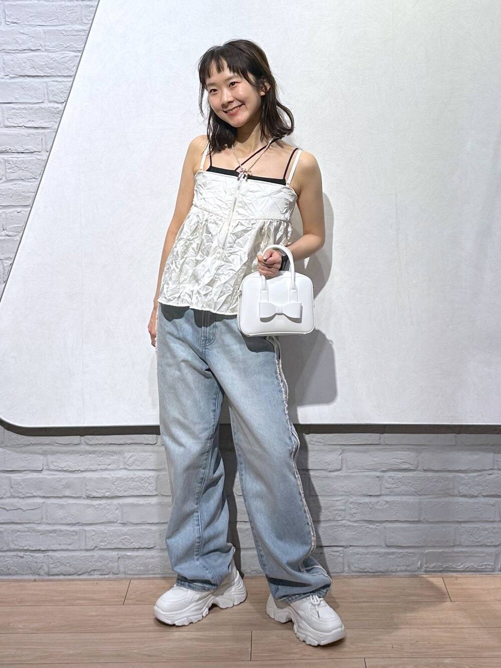 ホワイト系のスニーカー、ブラック系のキャミソール、ホワイト系のボストンバッグを着用したレディースの秋コーディネートの1枚目の写真