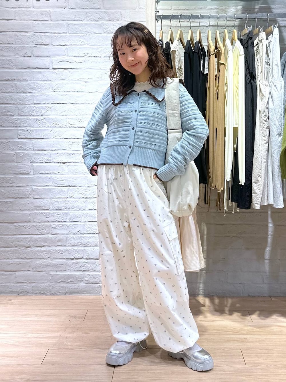 ベージュ系のショルダーバッグ、ホワイト系のTシャツ/カットソー、ブルー系のニット/セーターを着用したレディースの春コーディネートの1枚目の写真