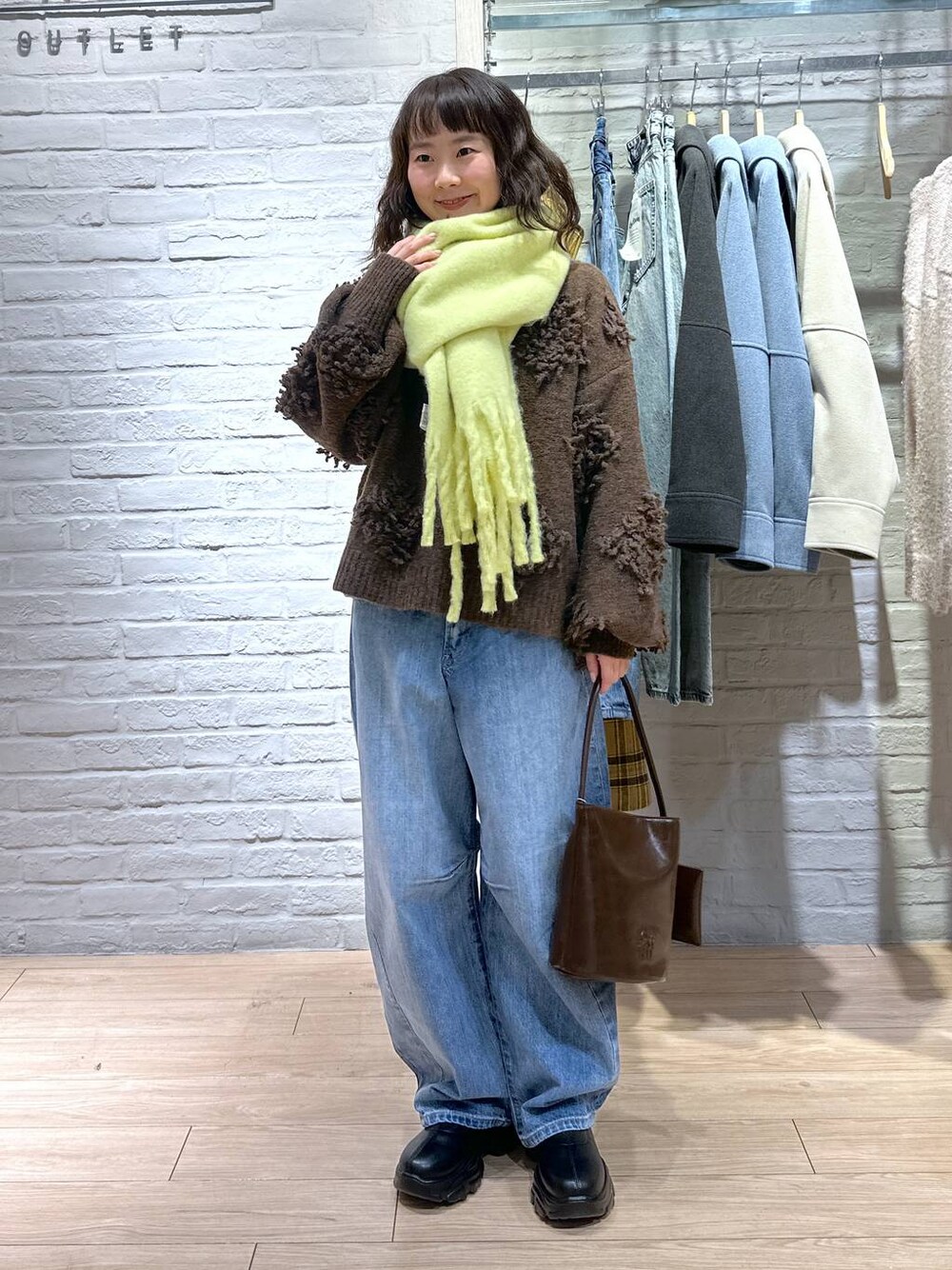 ブルー系のデニムパンツ、ブラック系のブーツ、ブラウン系のトートバッグを着用したレディースの冬コーディネートの1枚目の写真