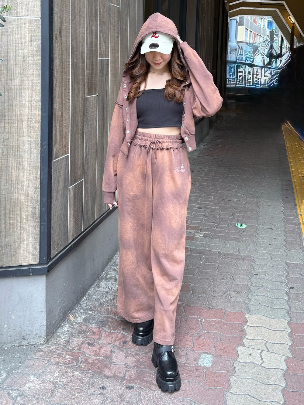 ブラウン系のスウェットパンツ、ブラック系のブーツ、ブラウン系のパーカーを着用したレディースの春コーディネートの1枚目の写真