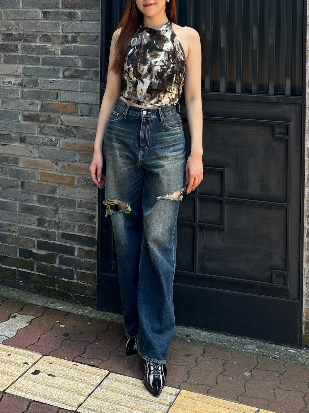 ブルー系のデニムパンツ、グリーン系のキャミソール、ブラック系のサンダルを着用したレディースの夏コーディネートの1枚目の写真