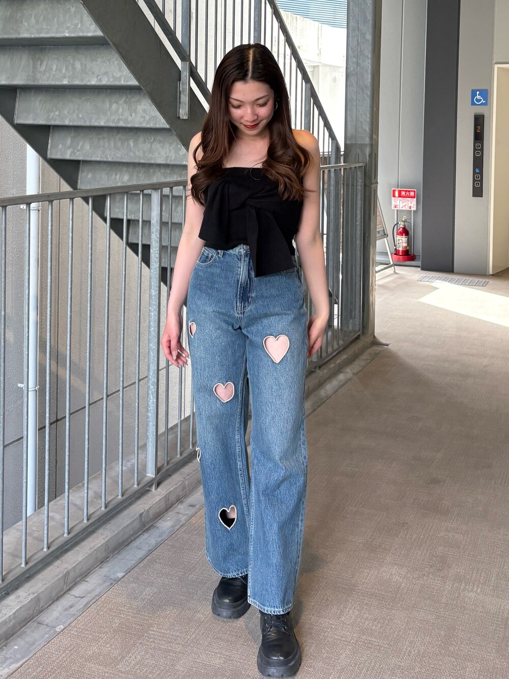 ブルー系のデニムパンツ、ブラック系のキャミソール、ブラック系のブーツを着用したレディースの春コーディネートの1枚目の写真