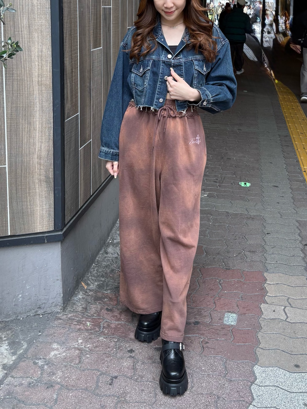 ブルー系のデニムジャケット、ブラウン系のスウェットパンツ、ブラック系のブーツを着用したレディースの春コーディネートの1枚目の写真