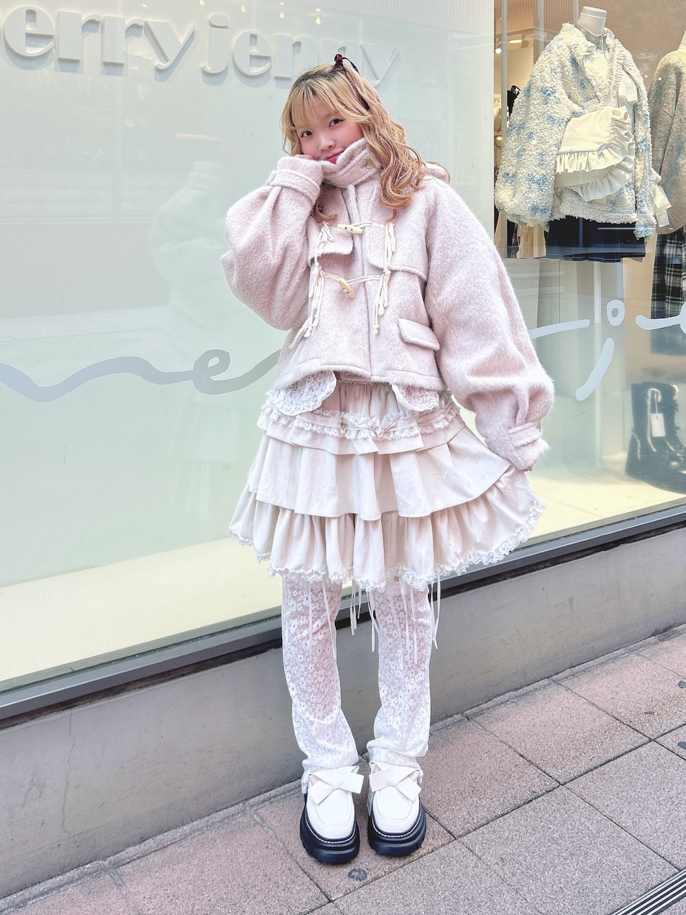 ホワイト系のスカート、ピンク系のダッフルコート、ホワイト系のカーディガン/ボレロを着用したレディースの秋コーディネートの1枚目の写真