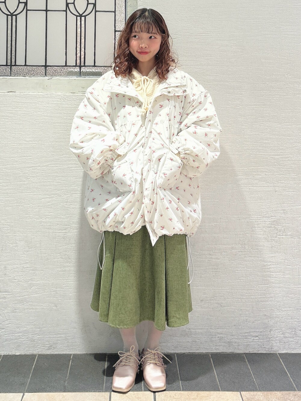 ピンク系のブルゾン、ホワイト系のニット/セーター、グリーン系のスカートを着用したレディースの秋コーディネートの1枚目の写真