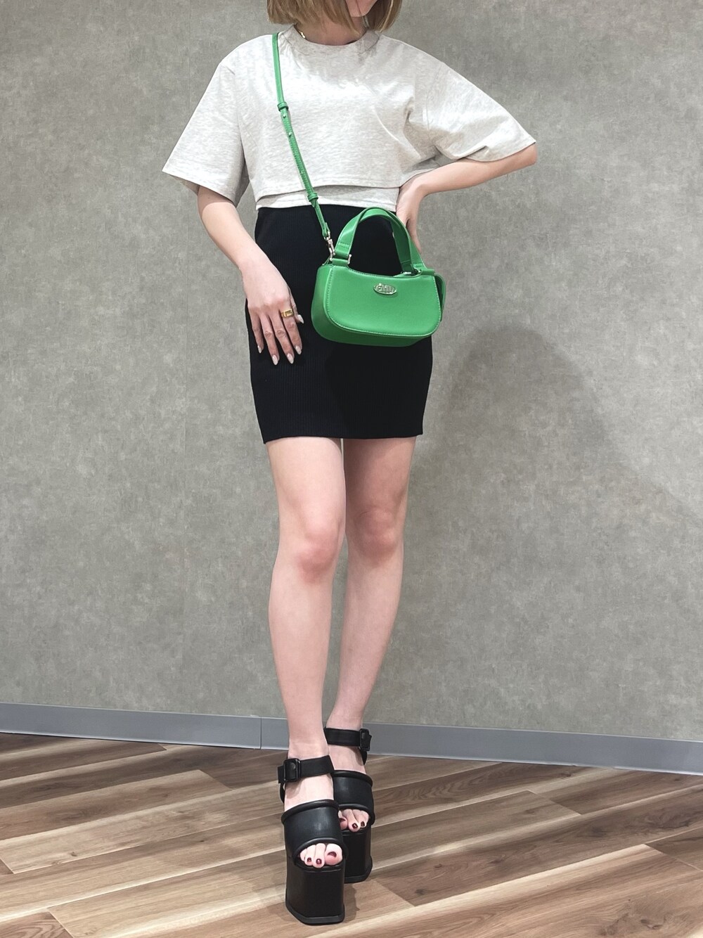 グレー系のTシャツ/カットソー、グリーン系のハンドバッグ、ブラック系のスカートを着用したレディースの春コーディネートの1枚目の写真