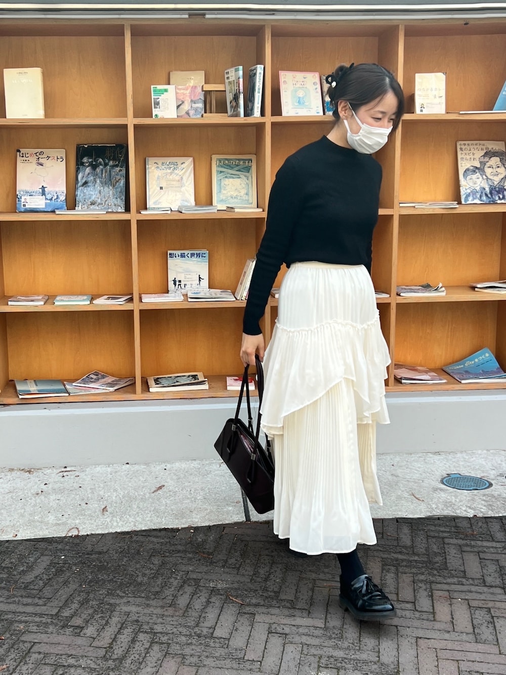 ブラック系のニット/セーター、ホワイト系のスカート、レッド系のハンドバッグを着用したレディースの冬コーディネートの1枚目の写真