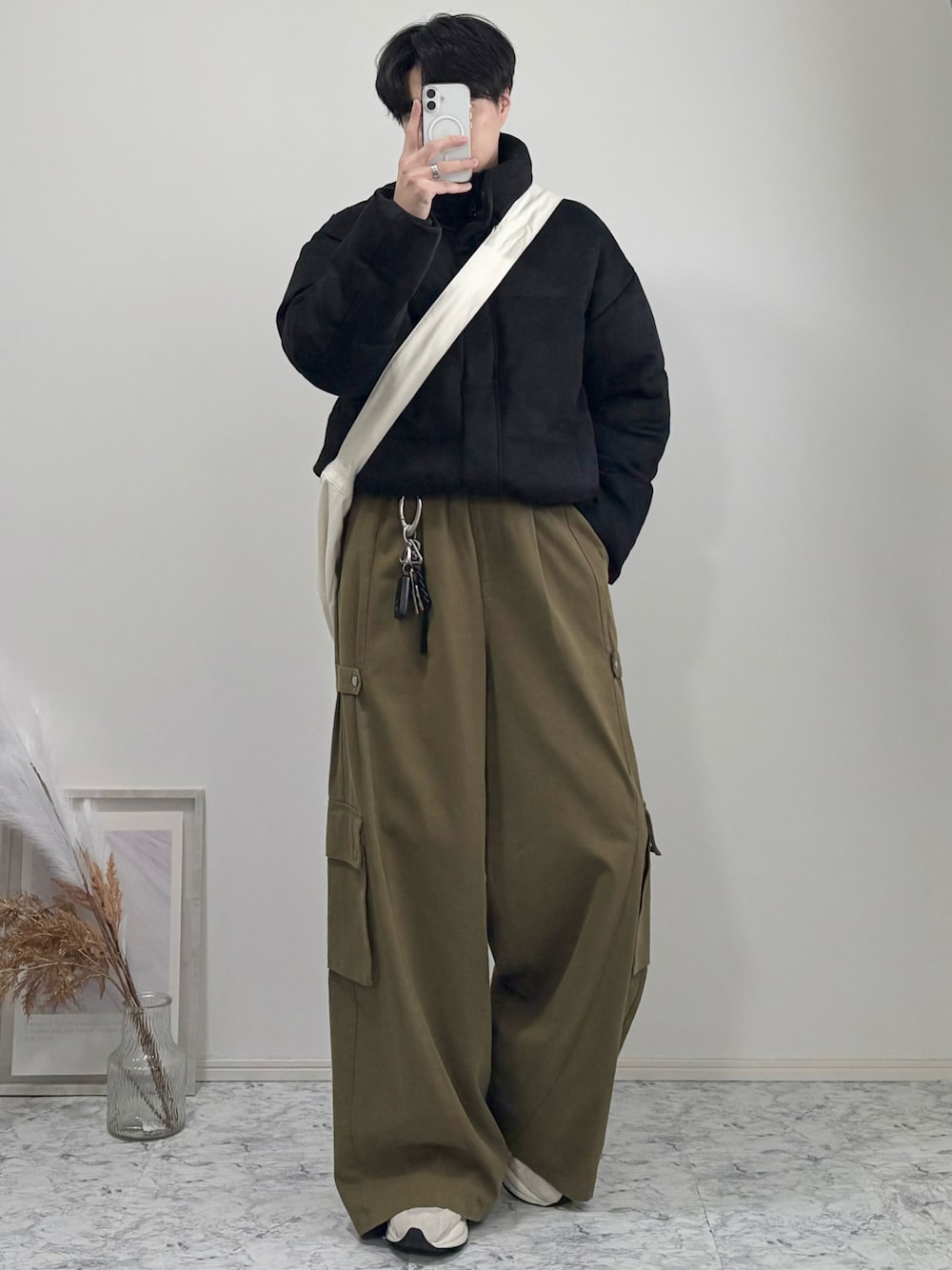 ベージュ系のショルダーバッグ、ブラック系のダウンジャケット/コート、グリーン系のカーゴパンツを着用したメンズの冬コーディネートの1枚目の写真