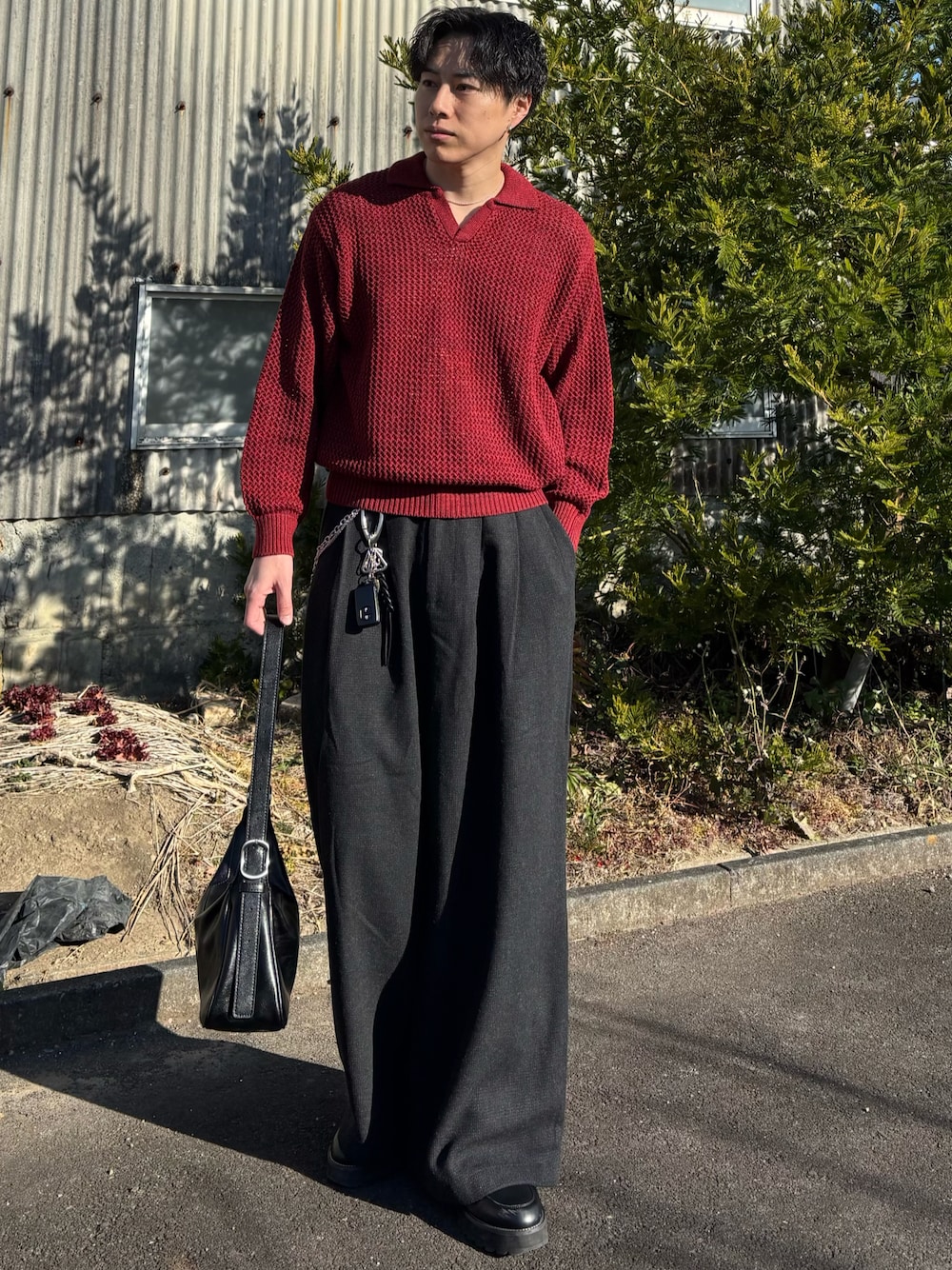 レッド系のニット/セーター、ブラック系のスウェットパンツ、ブラック系のショルダーバッグを着用したメンズの春コーディネートの1枚目の写真