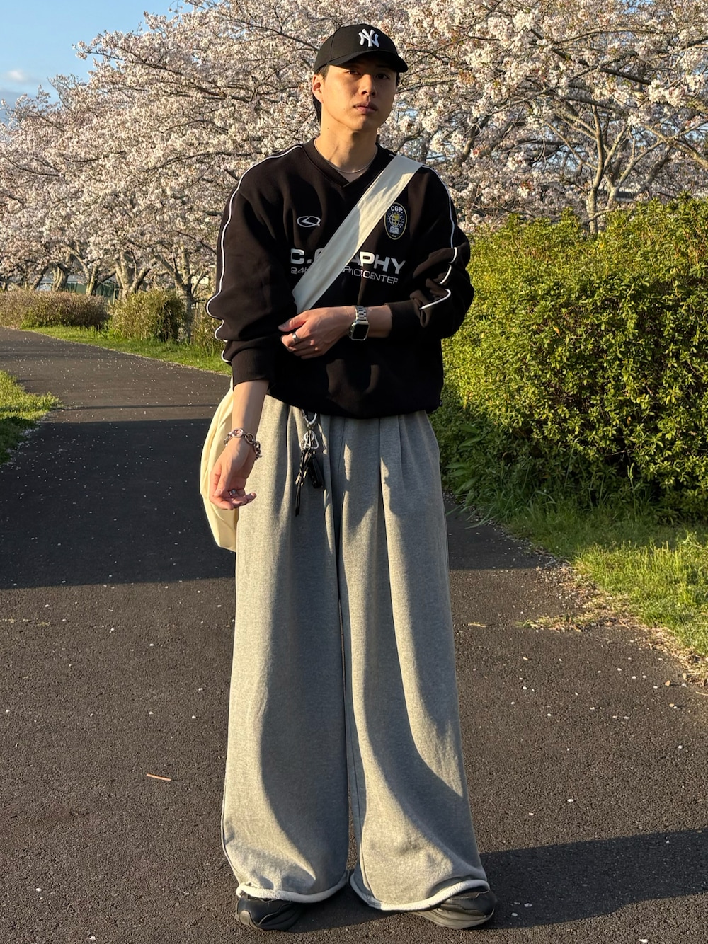 ブラック系のスウェット、グレー系のスウェットパンツ、ベージュ系のショルダーバッグを着用したメンズの春コーディネートの1枚目の写真