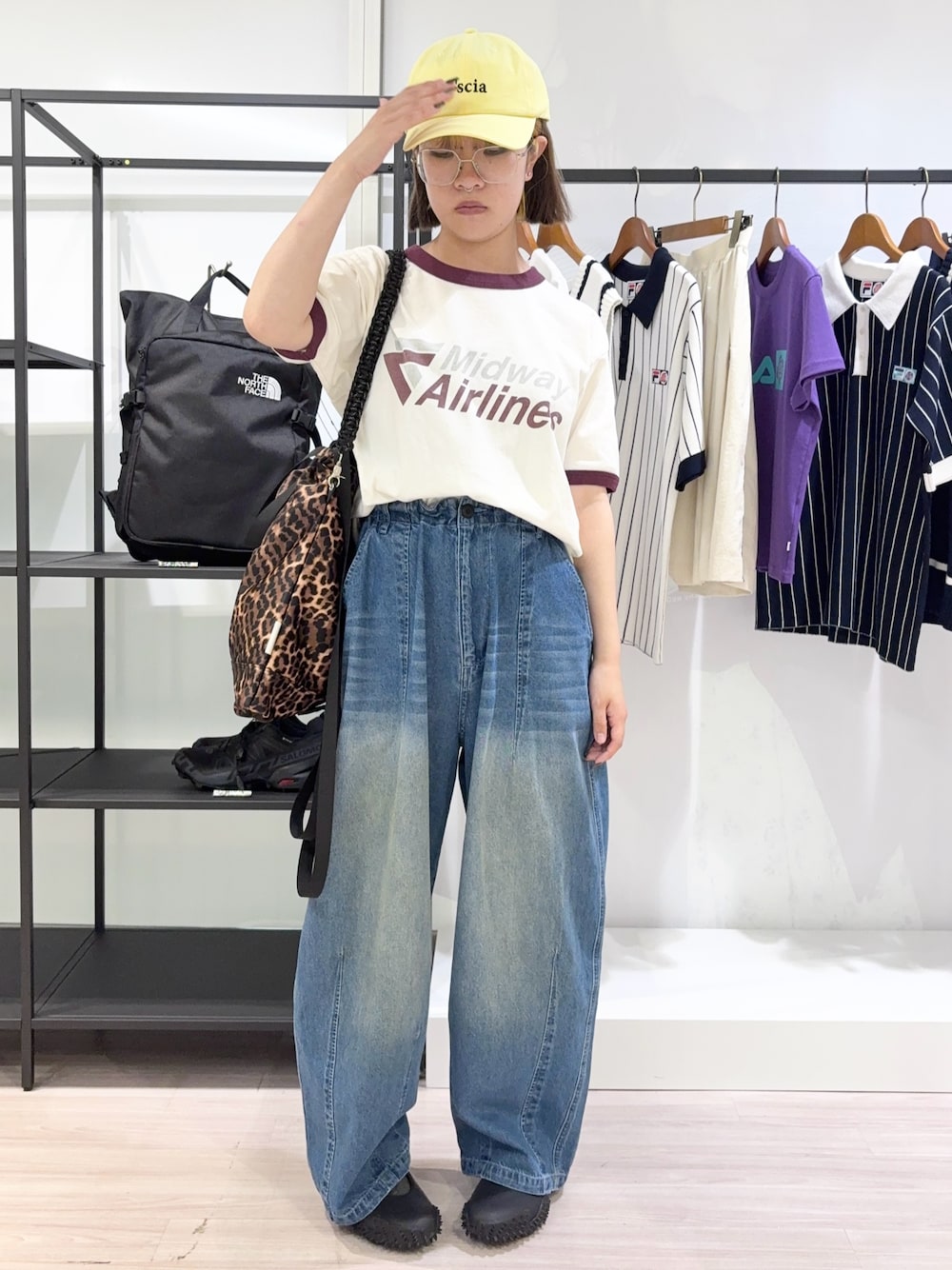 ブラウン系のトートバッグ、ブルー系のデニムパンツ、ブラック系のスニーカーを着用したレディースの夏コーディネートの1枚目の写真
