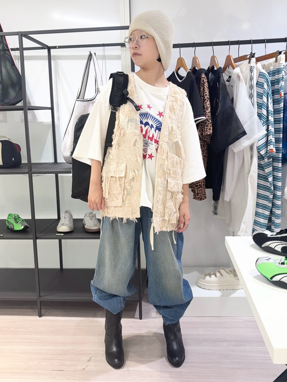 ベージュ系のベスト、ブラック系のバックパック/リュック、ブルー系のデニムパンツを着用したレディースの夏コーディネートの1枚目の写真