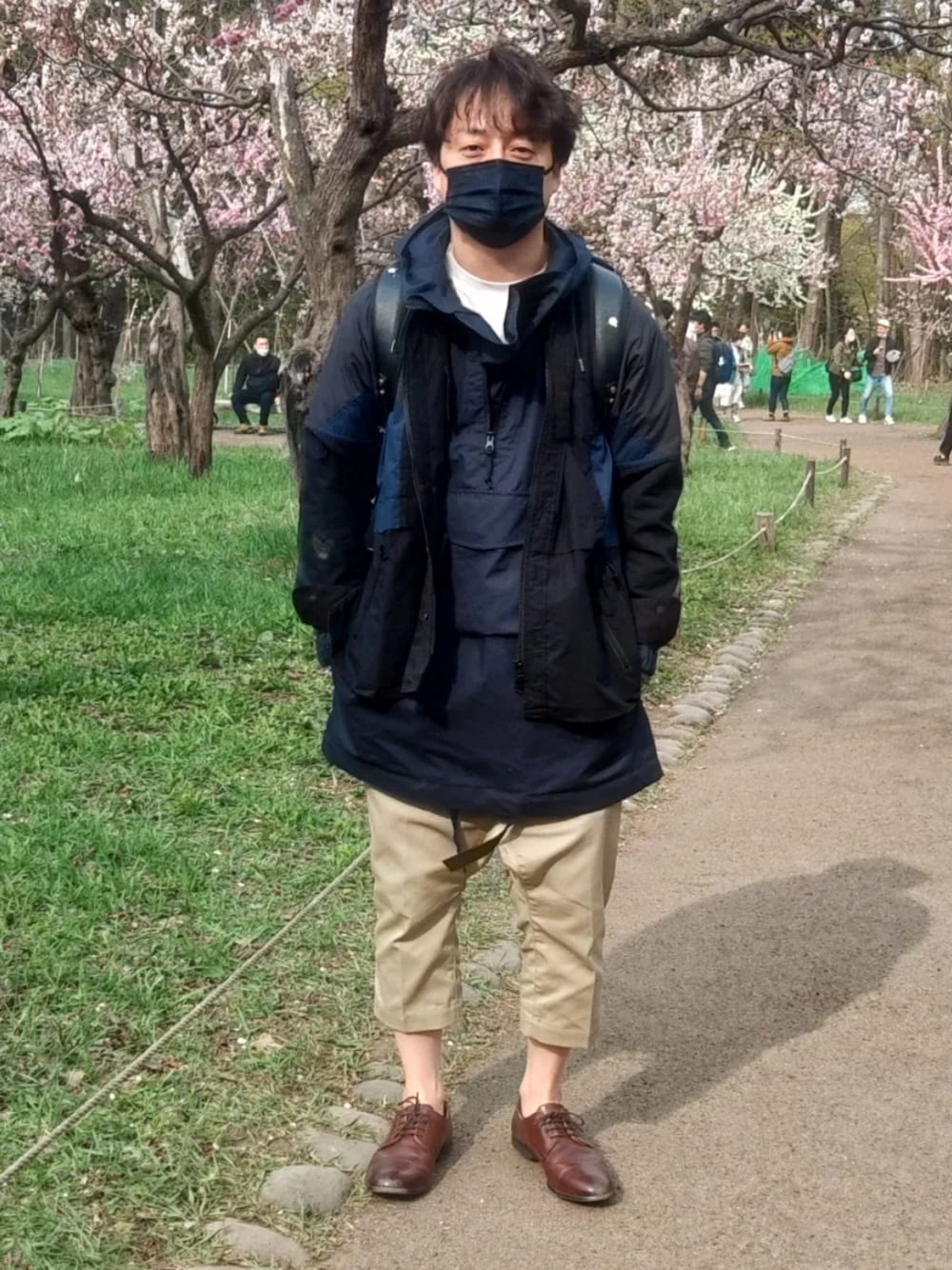 ブラウン系のその他シューズ、ベージュ系のチノパンツ、ブラック系のその他アウターを着用したメンズの春コーディネートの1枚目の写真