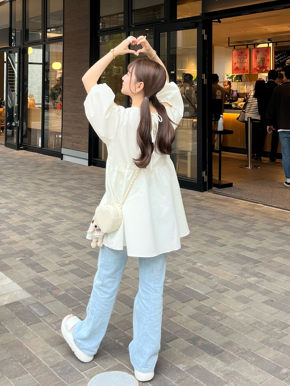 ホワイト系のシャツ/ブラウス、ホワイト系のショルダーバッグ、ブルー系のデニムパンツを着用したレディースの夏コーディネートの1枚目の写真