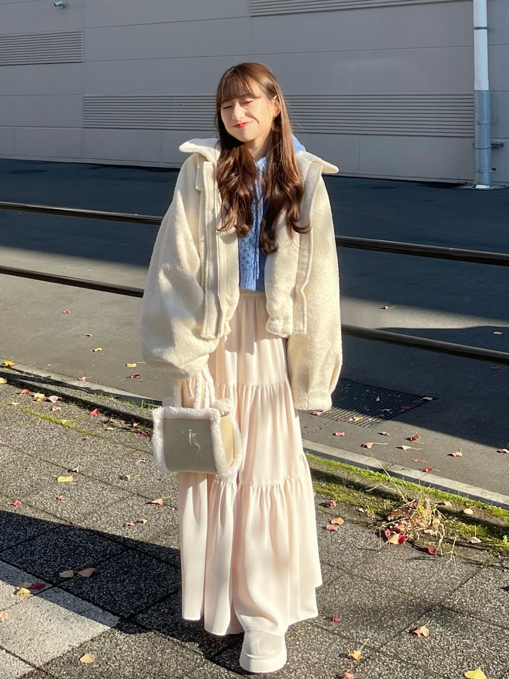 ホワイト系のスカート、ホワイト系のハンドバッグ、ホワイト系のステンカラーコートを着用したレディースの冬コーディネートの1枚目の写真