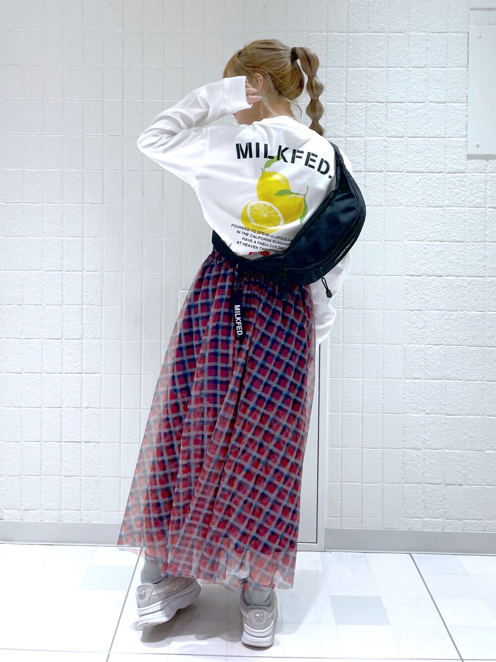 レッド系のスカート、ホワイト系のTシャツ/カットソー、ブラック系のボディバッグ/ウエストポーチを着用したレディースの秋コーディネートの1枚目の写真