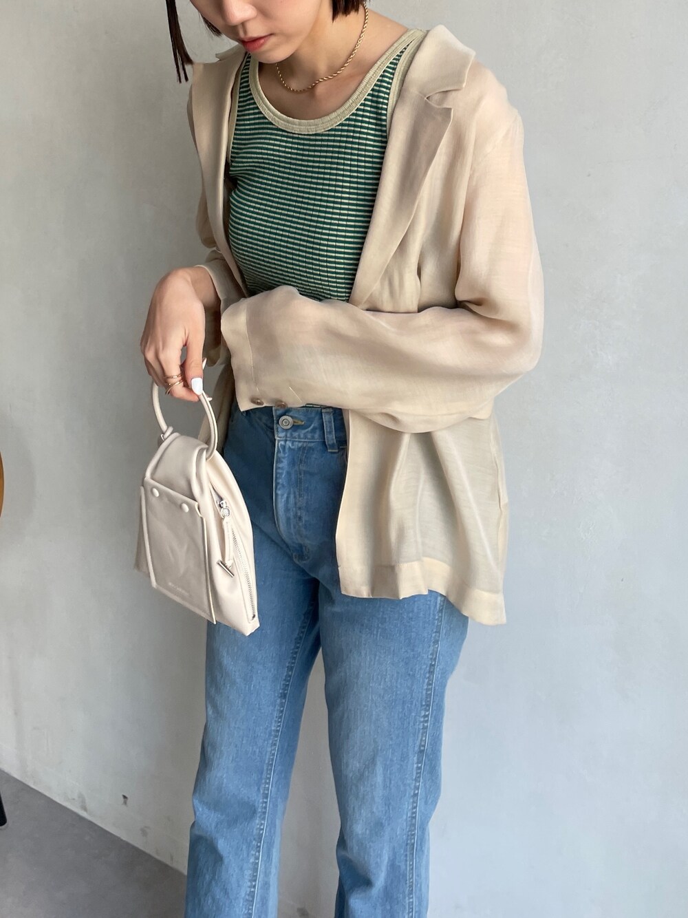 ブルー系のデニムパンツ、グリーン系のタンクトップ、ベージュ系のテーラードジャケットを着用したレディースの春コーディネートの2枚目の写真