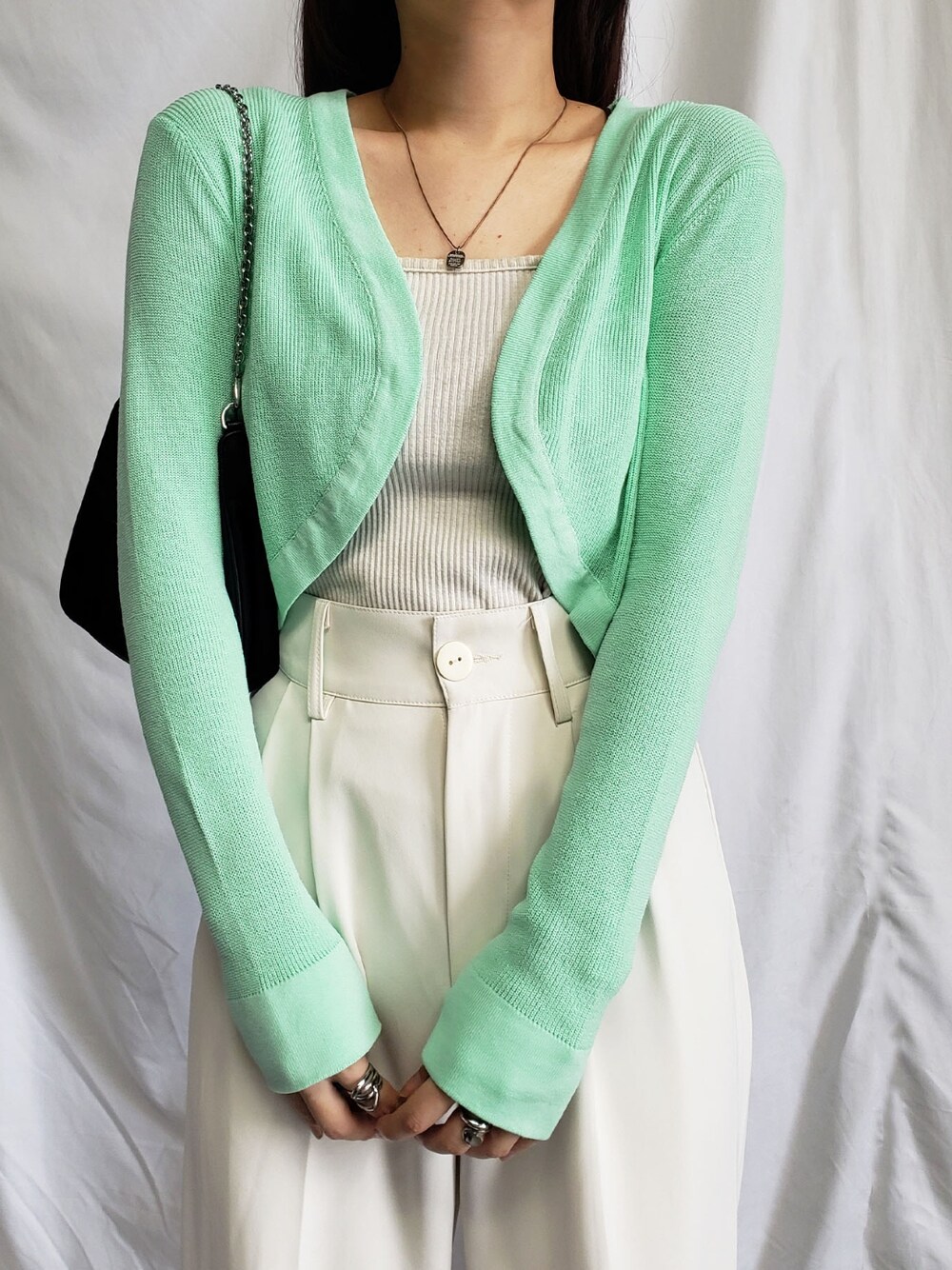 グリーン系のカーディガン/ボレロ、ホワイト系のスラックスを着用したレディースの夏コーディネートの1枚目の写真
