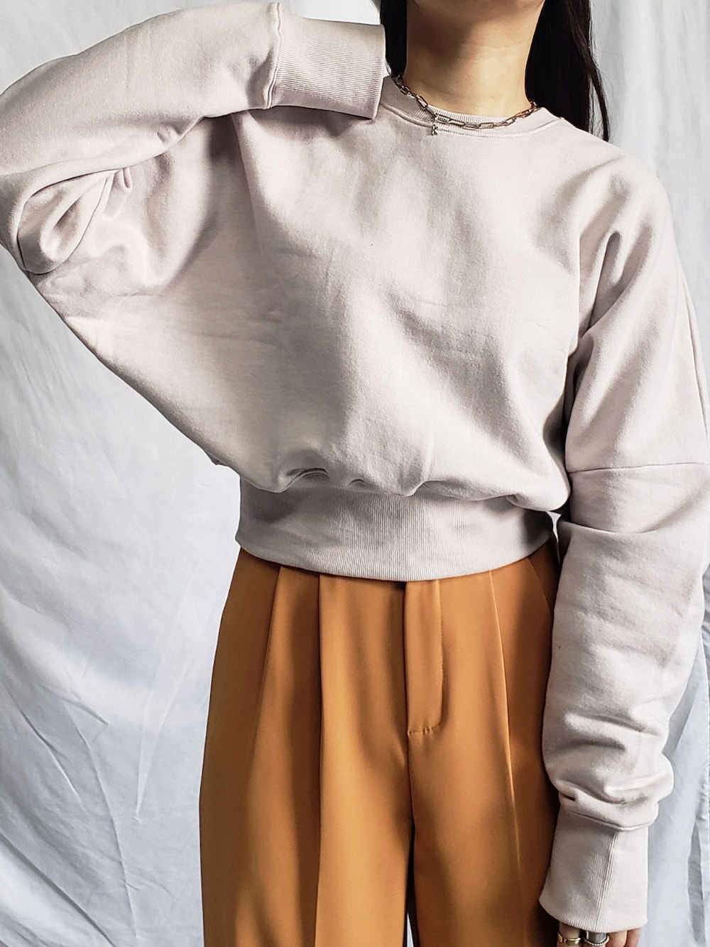 グレー系のスラックス、グレー系のスウェット、ブラック系のショルダーバッグを着用したレディースの冬コーディネートの3枚目の写真