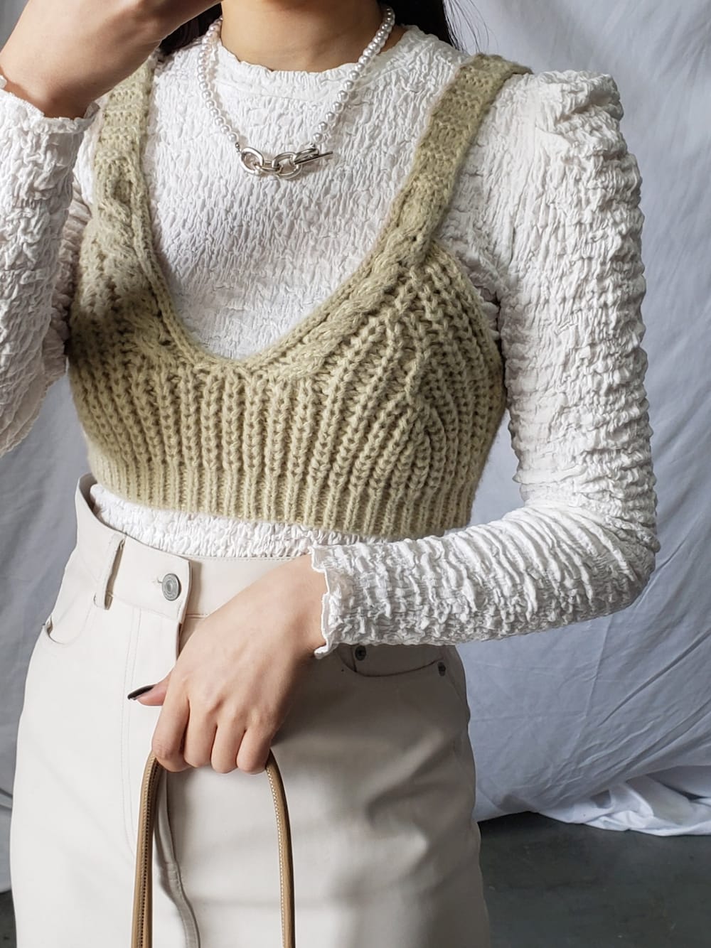 ホワイト系のスラックス、ブラック系のショルダーバッグ、ブルー系のTシャツ/カットソーを着用したレディースの冬コーディネートの3枚目の写真