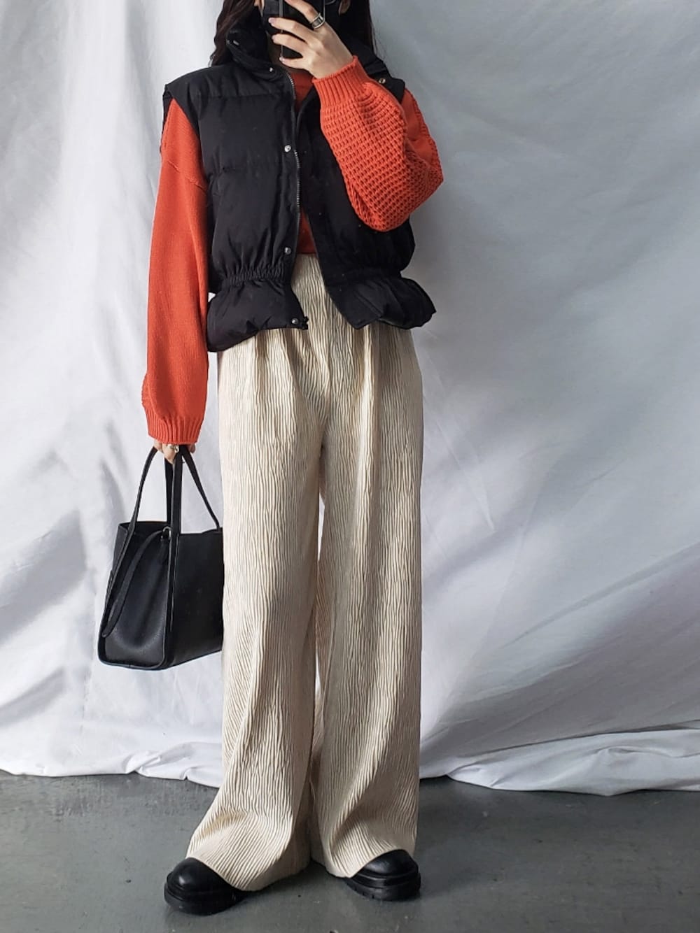 ホワイト系のその他パンツ、ブラック系のベスト、ブラック系のショルダーバッグを着用したレディースの冬コーディネートの1枚目の写真